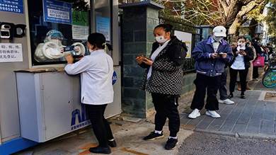 أشخاص يصطفون لتسجيل بياناتهم الشخصية قبل إجراء اختبار فيروس كورونا في بكين
